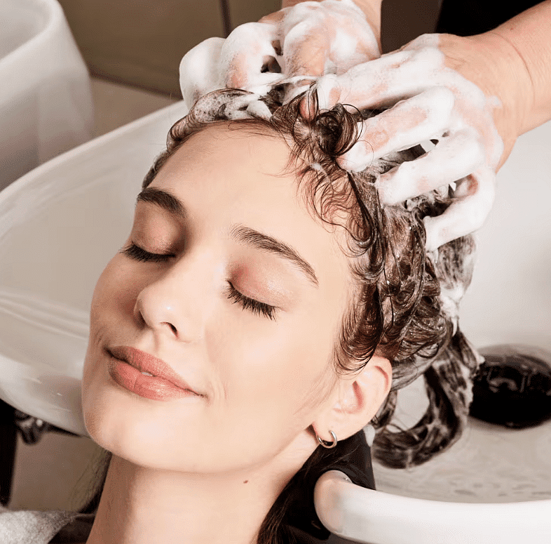 Woman enjoys a relaxing, sudsy hair wash at a salon.