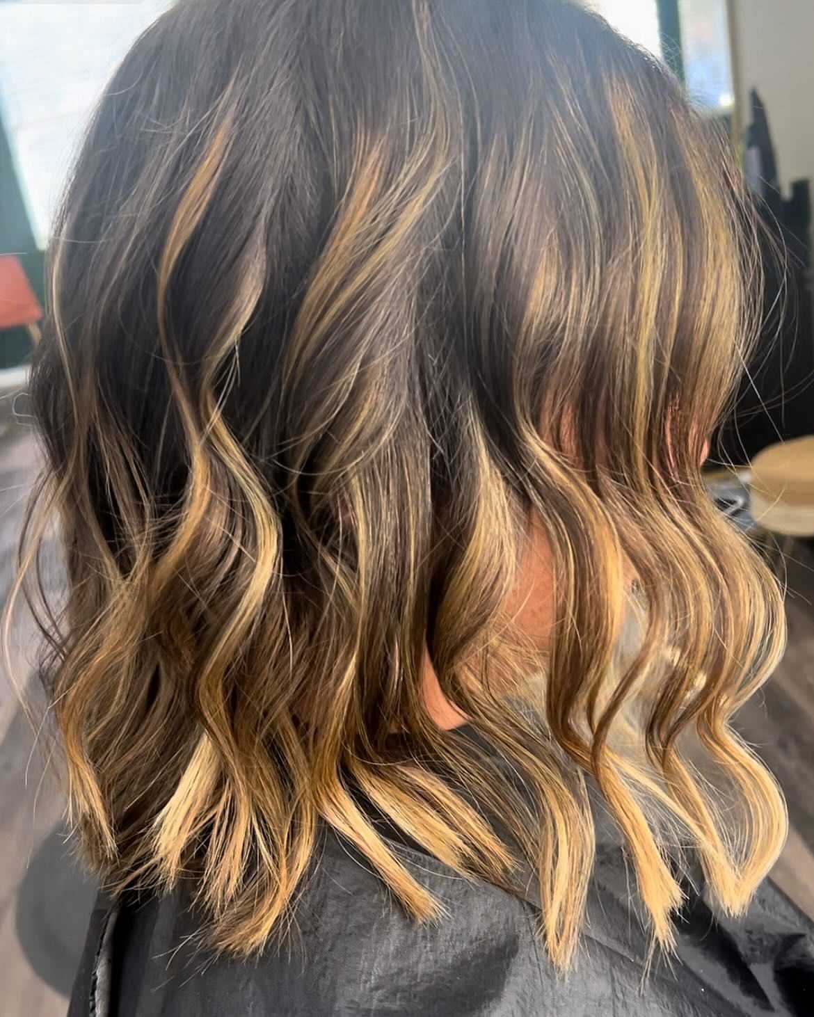 Close-up of a woman with shoulder-length wavy hair featuring blonde highlights.