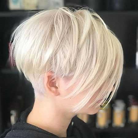 Short blonde bob hairstyle with long bangs covering the face, set against a dark background.