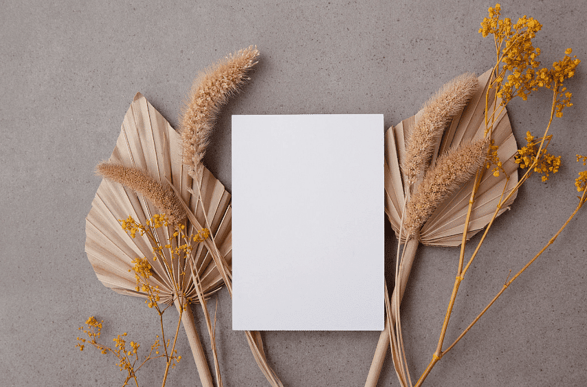 Blank white card with dried flowers on a gray background.