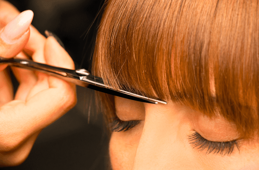 Close-up of a haircut, scissors trimming a person's bangs.
