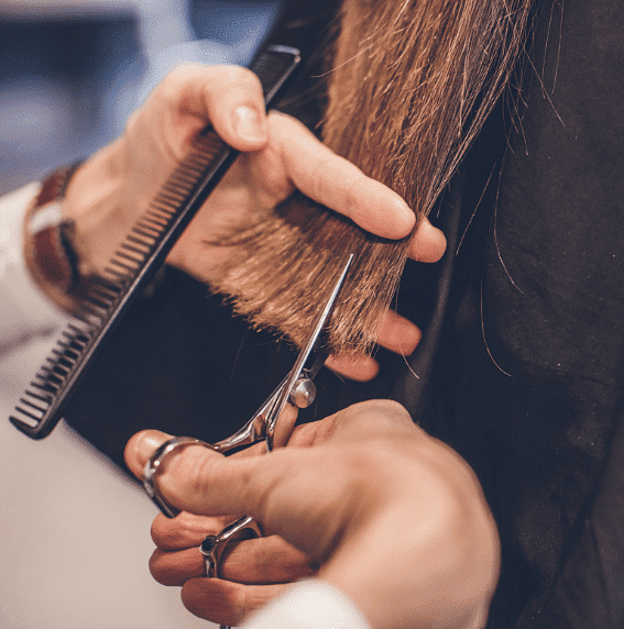 Hairdresser trimming a client's hair with scissors.