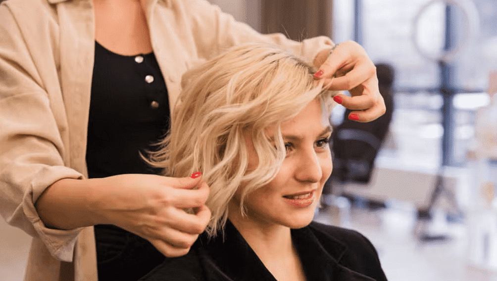 Person getting their hair styled in a salon by a hairstylist.